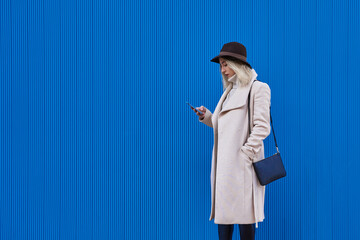 Attractive woman in a hat sending a message with her cell phone.