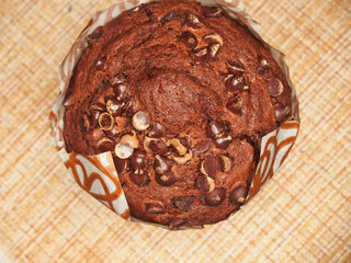 A cupcake, sprinkled with pieces of chocolate, is on the table.