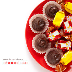 Assorted chocolates candy with sweet cream inside on a red plate, top view