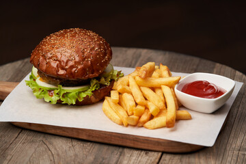 Big burger and fries on wooden table