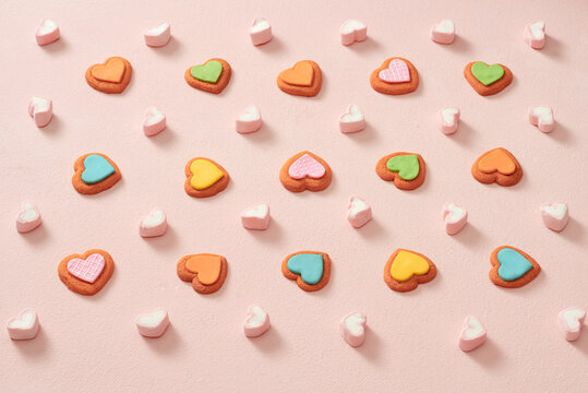 Composition with decorated heart shaped cookies on color background.