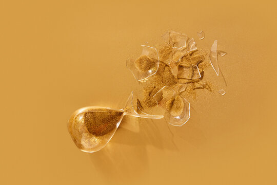 Crashed sandglass with golden sand.
