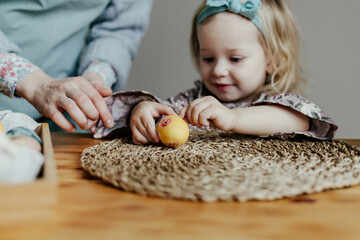 Child decorating egg with sticker on Easter
