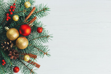 Christmas background with spruce branches, red berries, cones, cinnamon sticks and red and golden balls. Holiday concept.
