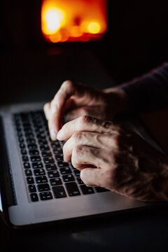 Man working on laptop at night near fireplace
