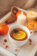 A wooden tray with tea, tangerines, nuts and spices on a beige plaid. Winter breakfast. The concept of hygge.