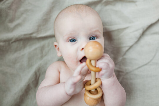 Baby boy playing with wooden rattle