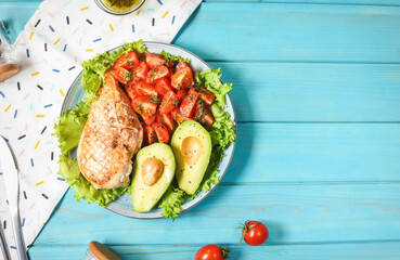 Caprese lunch bowl with grilled chicken and avocado on blue wooden background. Top view