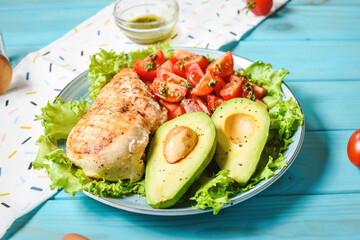 Caprese lunch bowl with grilled chicken and avocado on blue wooden background