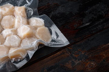 Scallops in vacuum pack, on dark wooden background  with copy space