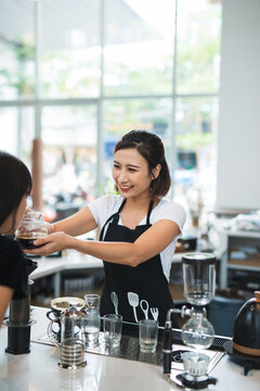 Asian barista help customer smelling coffee.