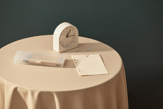 A cup of coffee next to note pad and alarm clock on table