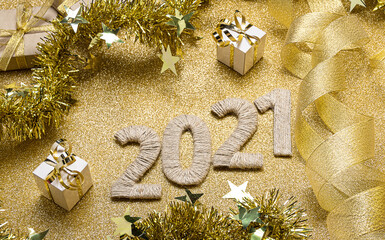 New Year card in gold colors. 2021 lettering decorated with ribbons and tinsel