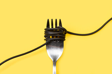 Tenedor con cable negro sobre un fondo amarillo liso y aislado. Vista superior. Copy space