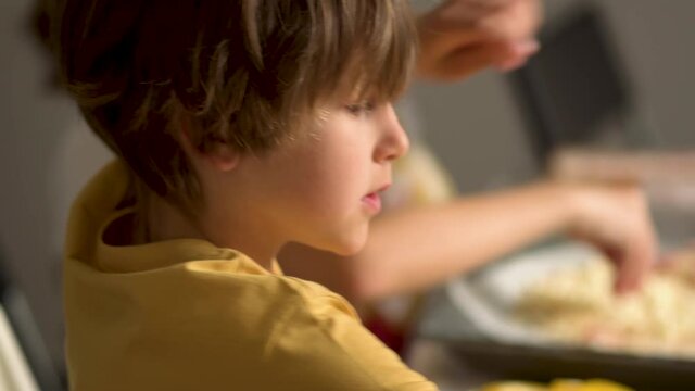 Children cooks pizza. Boy helps father. Prepering ingredients for pizza. Dad rubs cheese on a grater