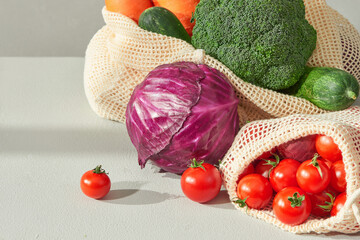 Mesh shopping bag with red tomatoes, bow and green cucumbers