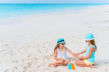 Fototapeta na wymiar UV protection. Sister puts sunscreen on her little sister's nose