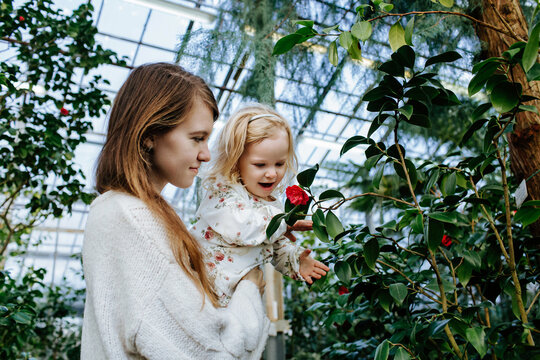 Mother and daughter smelling flower while walking in orangery