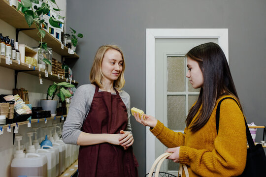 Seller offering buyer piece of soap to view in organic shop