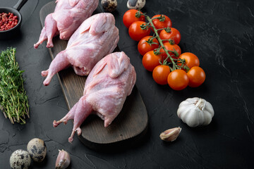 Fresh raw meat quails with herbs, on black textured background