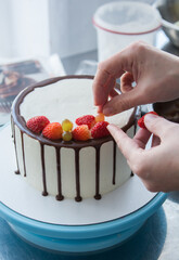 pastry chef decorates cake with strawberries