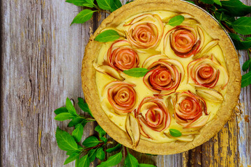 Fresh apple pie with decoration like a rose on wooden background.