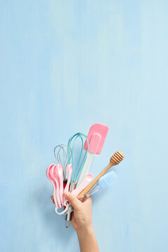 Baking flat lay. Female hands holding kitchen tools, sieve, rolling pin, spatula and bruch on pastel blue background. Banner with copy space. Top view.