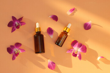 Different size and brown glass jars and bottles with massage and essential oils on bright color background. Beauty spa background concept.