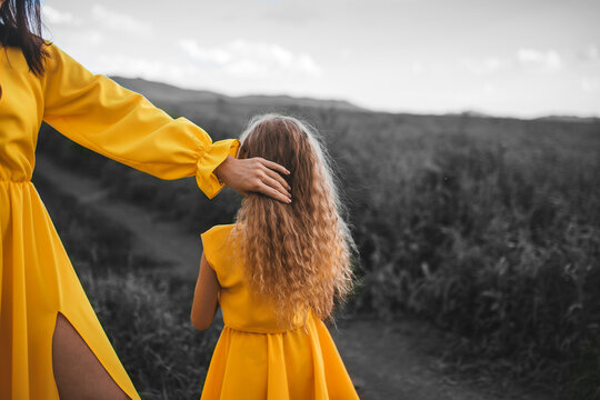 Small Kid With Mother In Yellow Illuminating Dresses On Gray Nature Background.