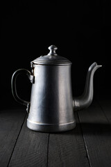 Old silver teapot with black background