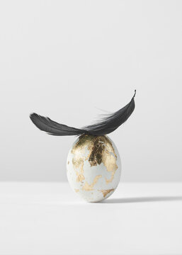 Golden painted egg with feather.