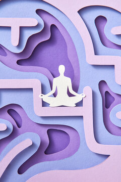 Paper meditating man is sitting on handmade paper structure of human brain.