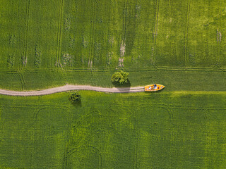 Yellow boat is moving along road by field.