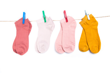 several colored socks hanging on a rope with clothespins isolated on white background