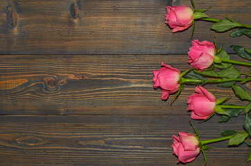 Fototapeta na wymiar Pink roses on a wooden background, a table. View from above. The concept of a floral background.