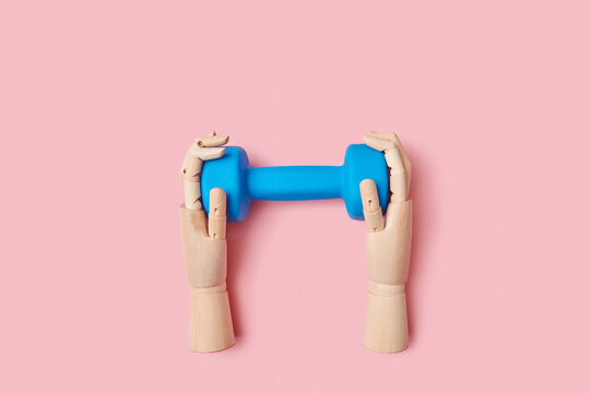 Wooden hands hold blue dumbbell.