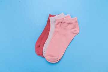 two pairs of multicolored new socks stacked on a blue background. top view.
