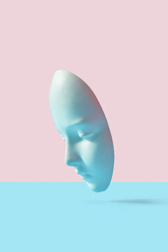 Vertically floating plaster theatrical mask.