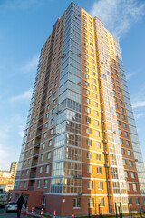 Fototapeta premium Modern multi-storey brick and glass residential building against the sky. In brown, beige. Construction.