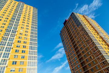 Obraz premium Modern multi-storey residential buildings made of bricks and glass against the background of the sky. In brown, beige. Construction.