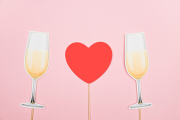 Valentine's day, love, romantic concept. Red heart and champagne glasses paper prop on pink background. Greeting card. Flat lay, top view, copy space