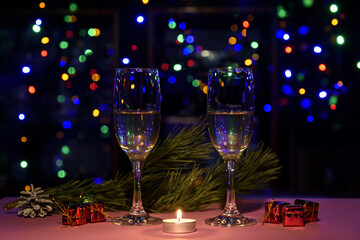 Two glasses of wine on the table. Christmas New Year lights and decorations.