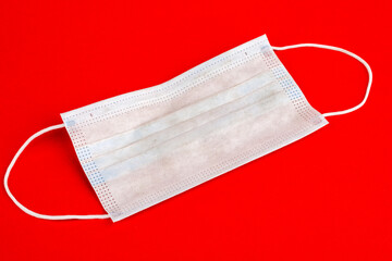 Medical mask, a medical protective mask isolated on a red background. A disposable surgical face mask covers the mouth and nose. Health care coronavirus medical quarantine, hygiene concept