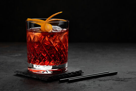 Classic Negroni Cocktail in a retro glass with ice and orange peel on a black background, space for text