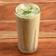 Masala Buttermilk drink or masala chaas, Made of yogurt. served in a glass over a rustic wooden background,a refreshing drink for summer days, selective focus on top
