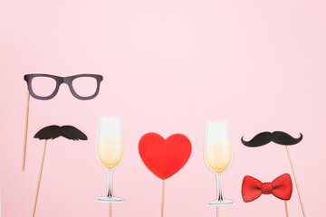 Valentine's day lgbt, love, romantic concept. Red heart, champagne glasses with couple paper mustache props on pink background. Greeting card. Flat lay, top view, copy space