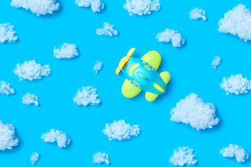 Airplain toy in a blue sky with cotton clouds.