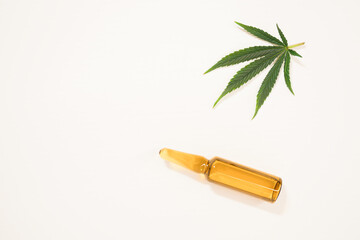 Ampoule with CBD oil on white background. Cannabis leaf flat lay isolated. Medical marijuana concept. Copy space