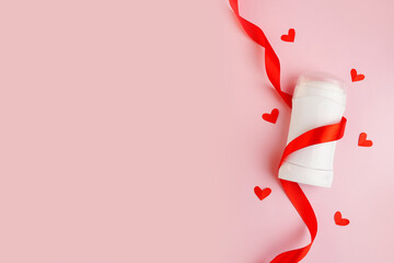 white deodorant with red hearts and ribbon on pink background. Top view. skin care with love. valentine's day