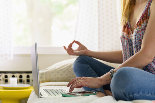 Woman Practicing Meditation on Bed at Laptop